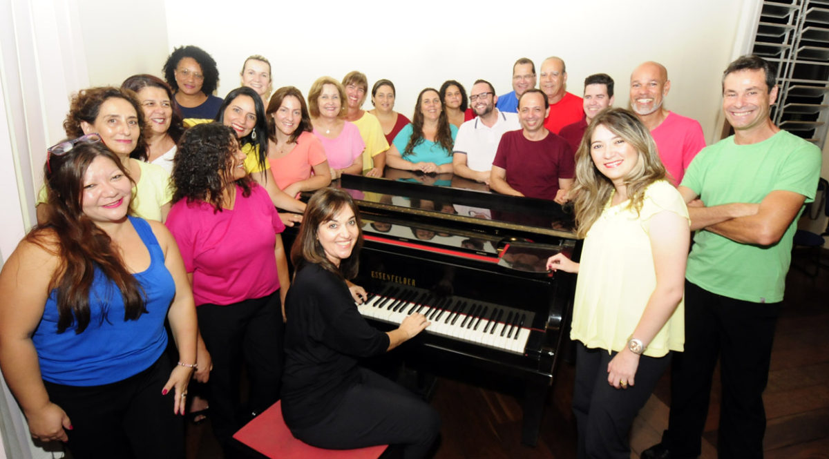 Coralistas do Coral Municipal em foto posada em volta de um piano