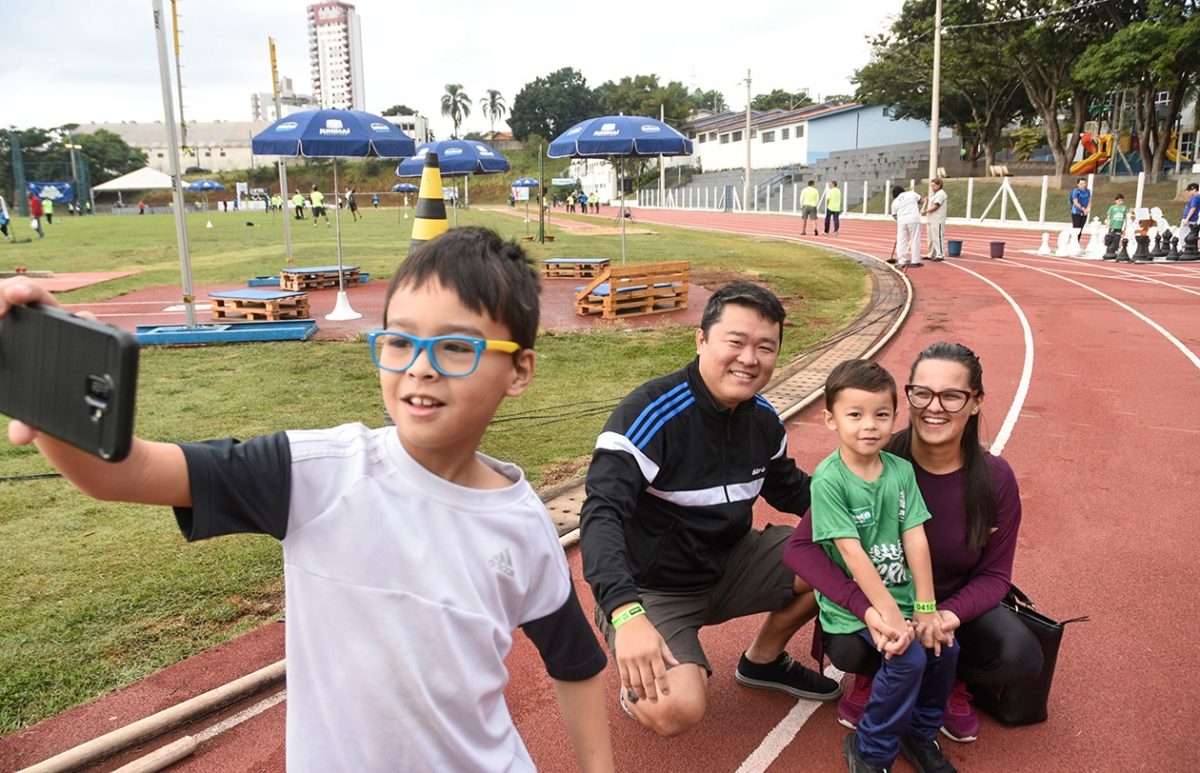 Garoto faz selfie com a família, agachada na pista de corrida do Bolão
