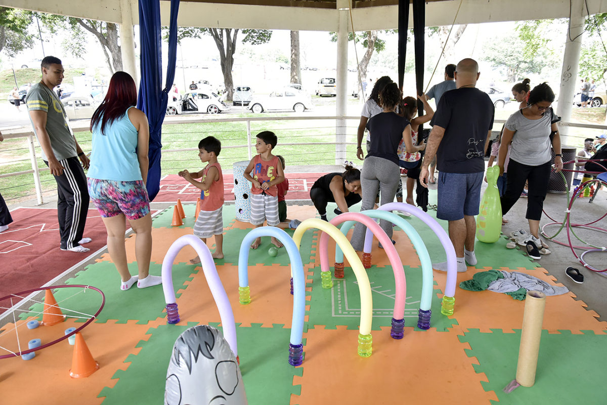Crianças e adultos, no coreto do parque, com brincadeiras e atividades infantis