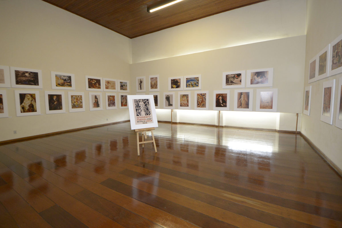 Sala de exposições da Pinacoteca, com reproduções de quadros e painel no centro, com o sÃmbolo da Semana de Arte Moderna de 1922