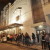 Fachada do Teatro Polytheama à noite, com público aguardando em fila