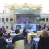 Praça do Coreto, com banda se apresentando no palco, e pessoas sentadas nas mesas comendo